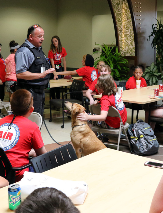 air camp student listening to teacher with training dog