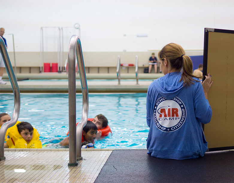 air camp student in a swimming pool with life coach sitting