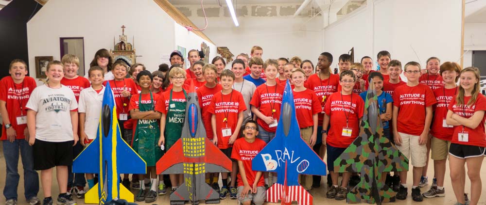 large group of air camp students standing with their painted airplane models