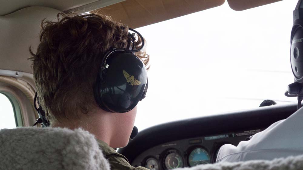 air camp student sitting in cockpit of airplane