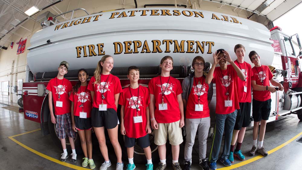 air camp student standing in front of a fire truck