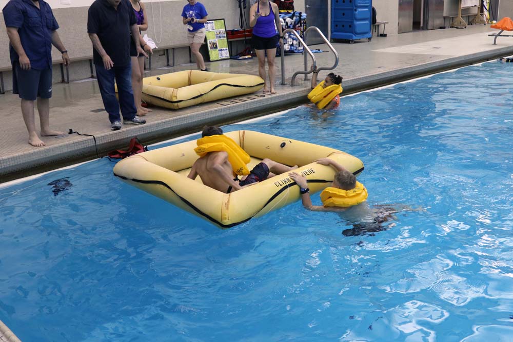 air camp students swimming in pool with a floating boat