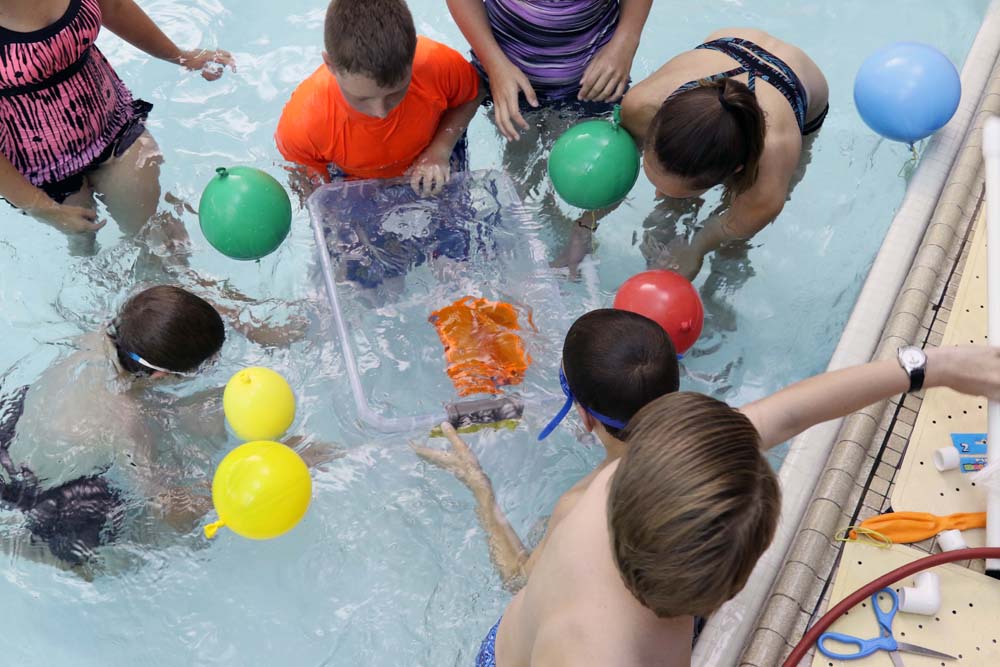 air camp students in pool with balloons trying a science experiment