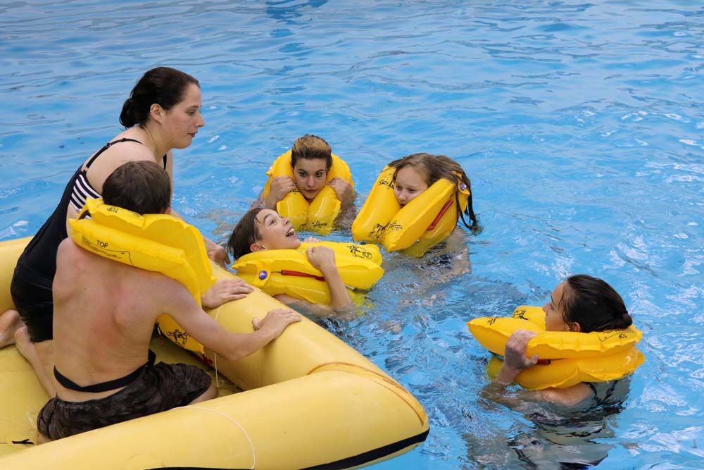 air camp students swimming in pool with a floating boat