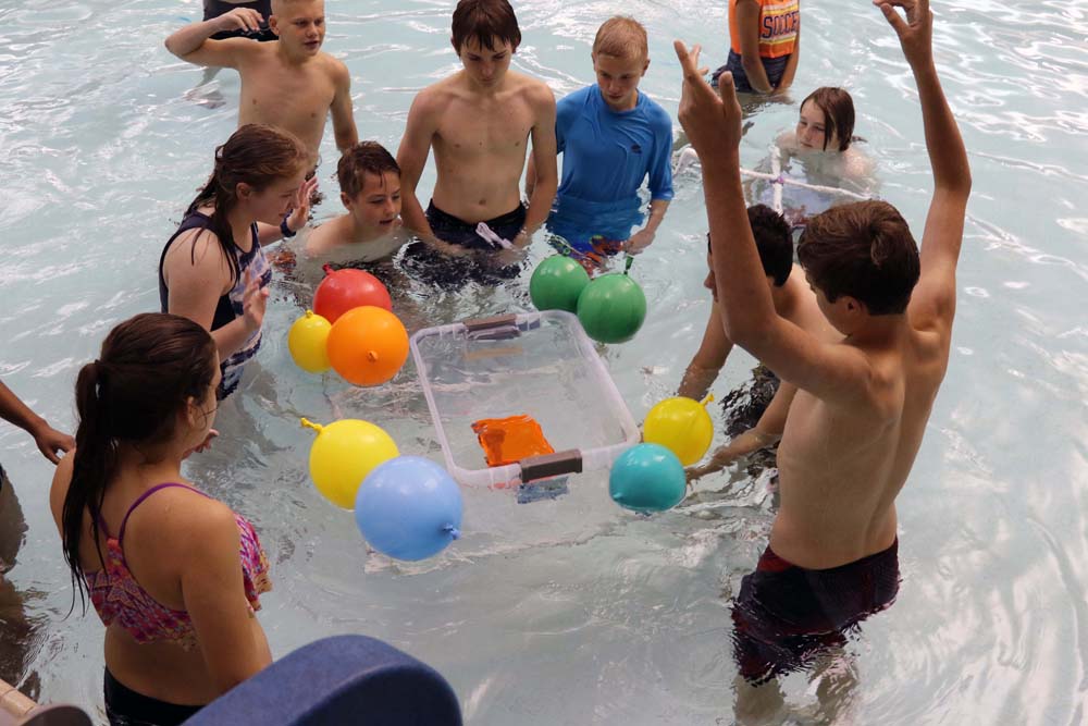 air camp students in pool with balloons trying a science experiment