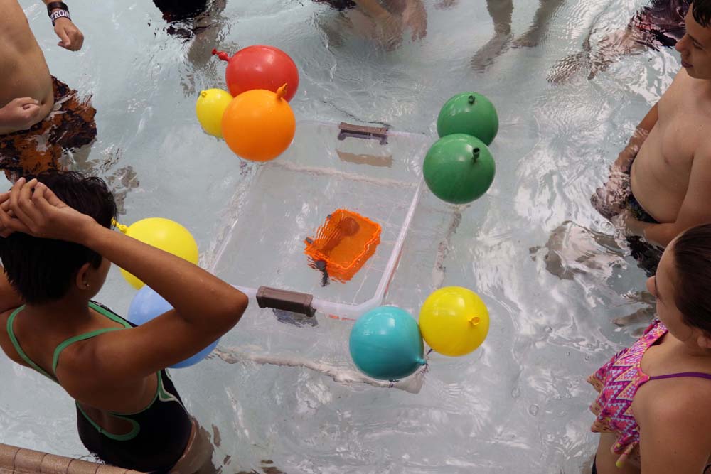 air camp students in pool with balloons trying a science experiment