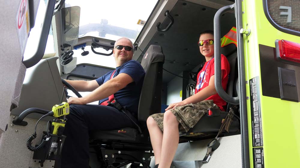 fire fighter and air camp student sitting in a fire truck