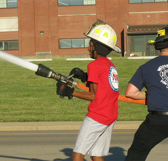 kid using a fire hose with fireman